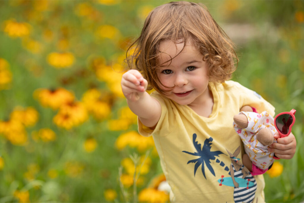 Young girl in field of flowers looking at camera.