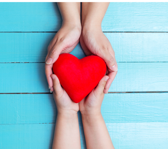 Young child and adult hands surrounding a heart
