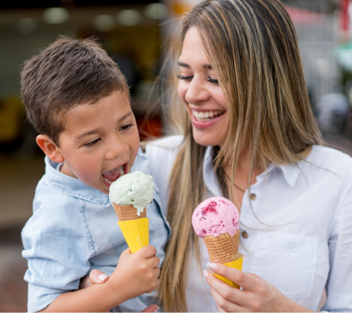 Boy in his mother's arm and both eating ice cream