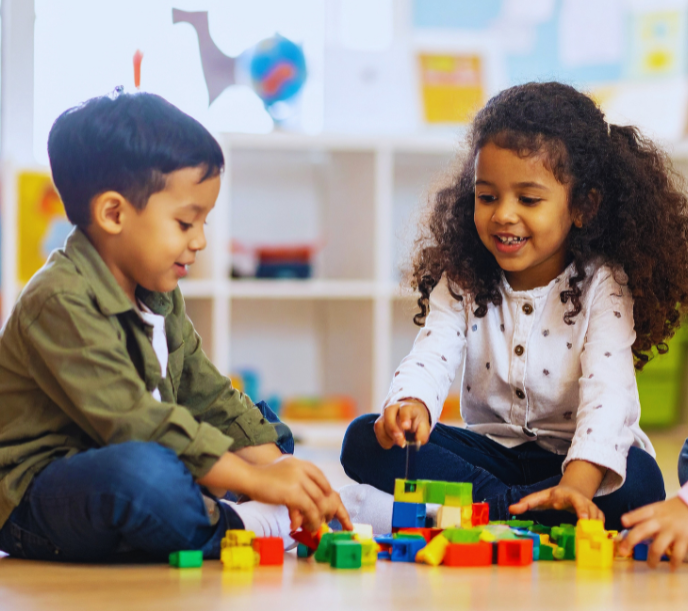 Young boy and young girl playing with colored blocks on the floor.