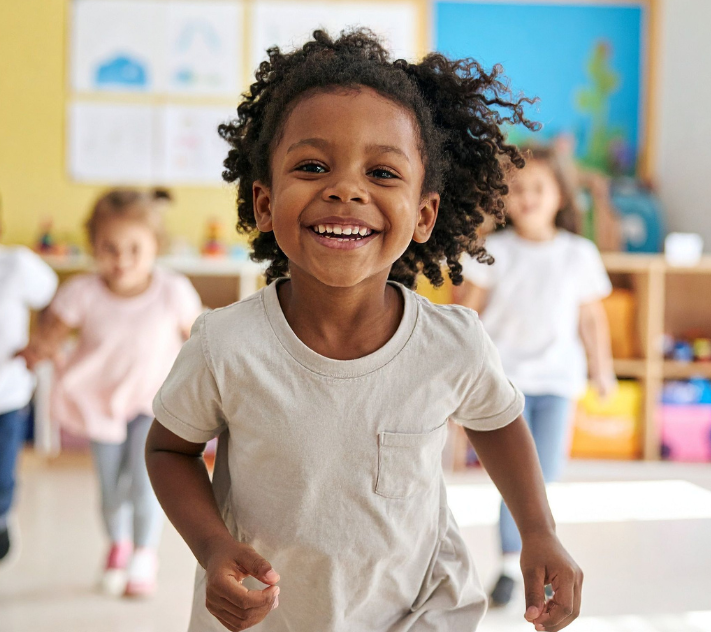 Young preschool child running and smiling with other children in the background