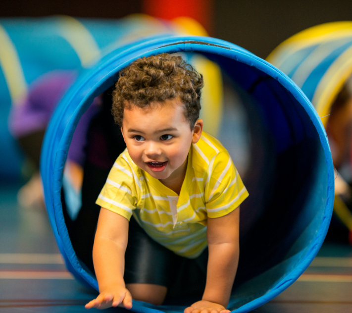 Young boy crawling through a play tunnel