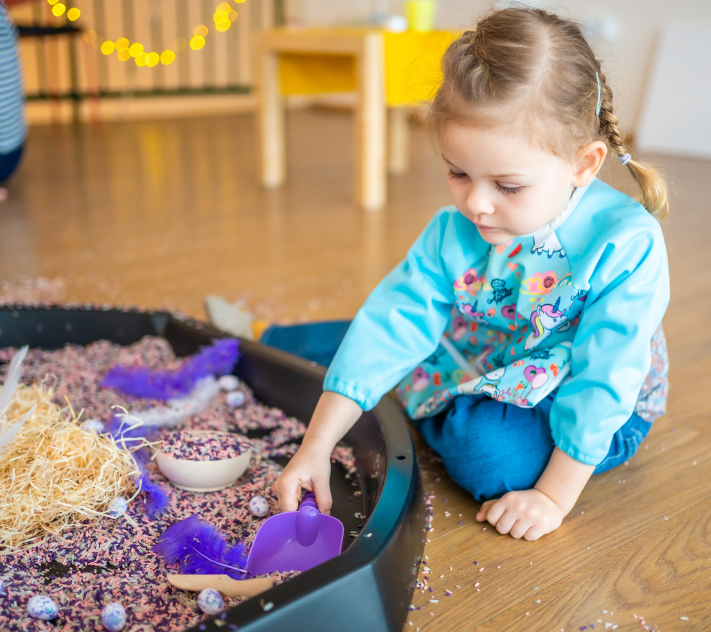 Young girl playing with objects in a sensory bin
