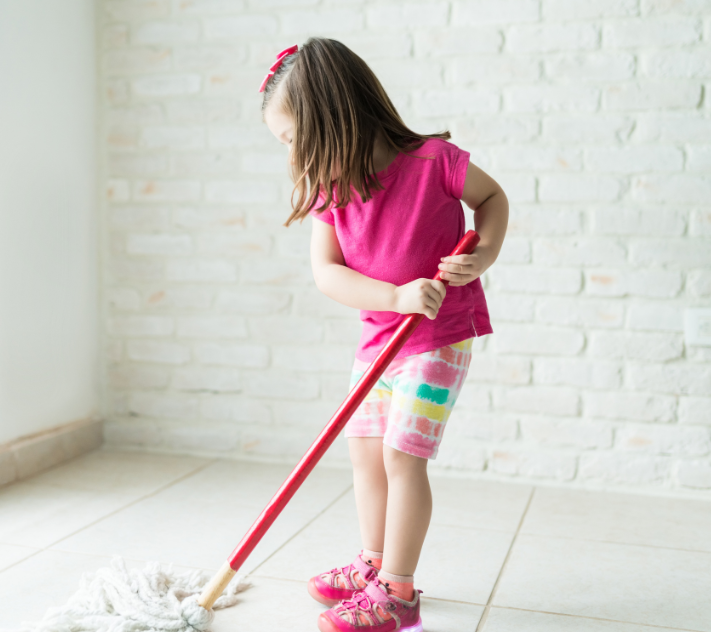 Young girl pretending to mop the floor