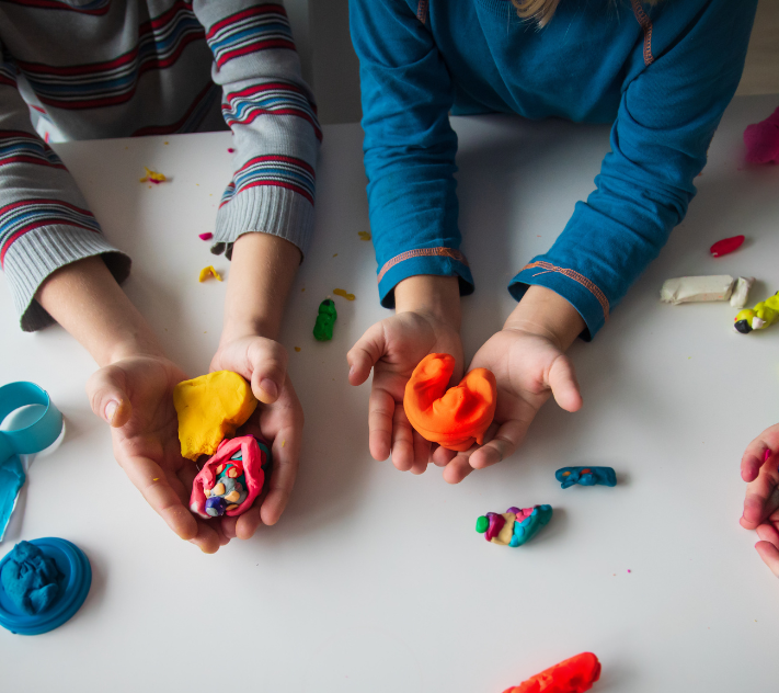 Young children's (only hands visible) playing with modeling play in a play-based preschool