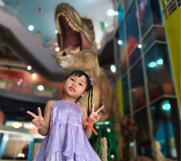 Young girl standing in front of a dinosaur statue