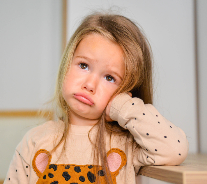 Young girl making a sad face with her hand on the side of her head and maki